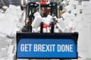 DEPARTURE: Prime Minister Boris Johnson drives a Union flag-themed JCB through a fake wall emblazoned with the word 