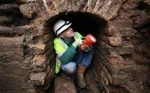 A worker crouches in the smugglers tunnel - which archaeologists suggest was used to move goods around into house in the town